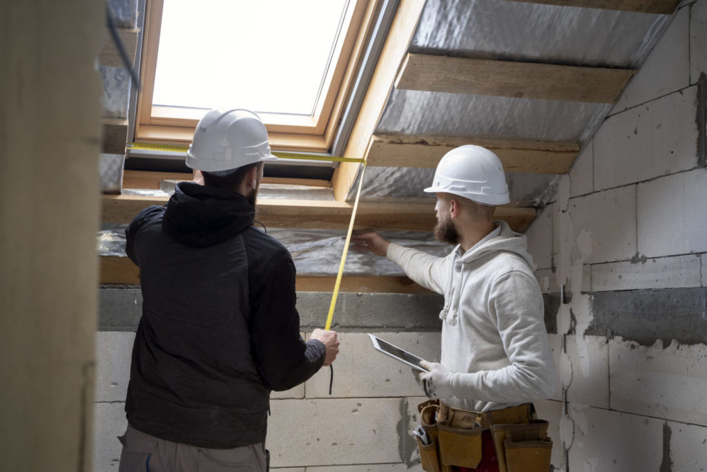 Zwei Handwerker beim Vermessen eines Dachs für die energetische Sanierung