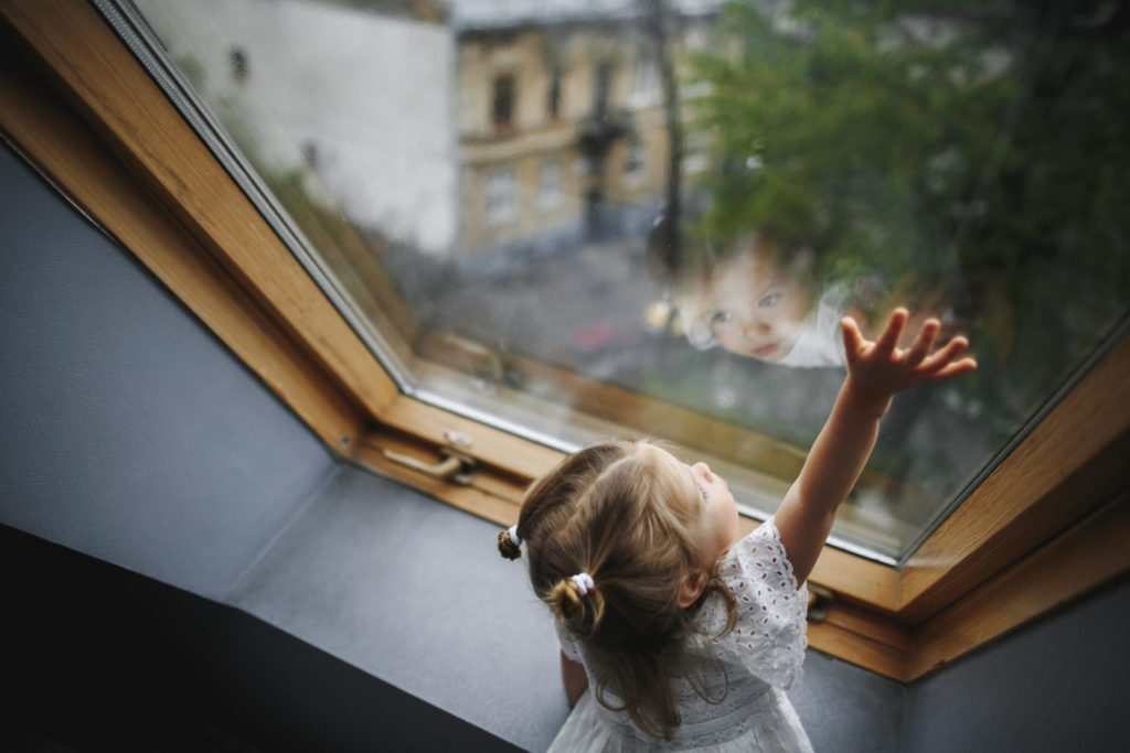 Kind schaut aus großem Fenster einer Neubauwohnung